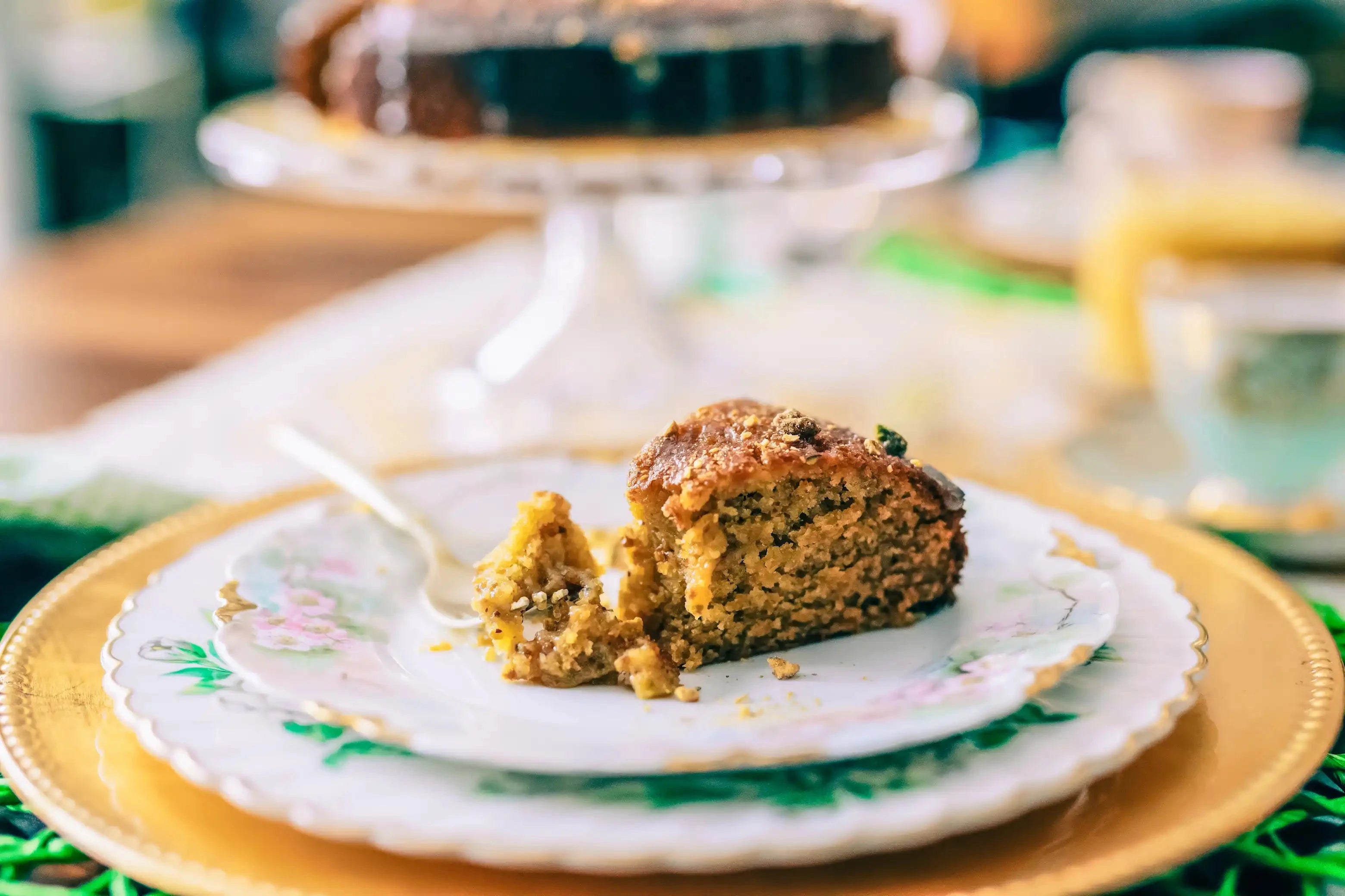 piece of honey olive oil pistachio cake on a plate with bite on fork
