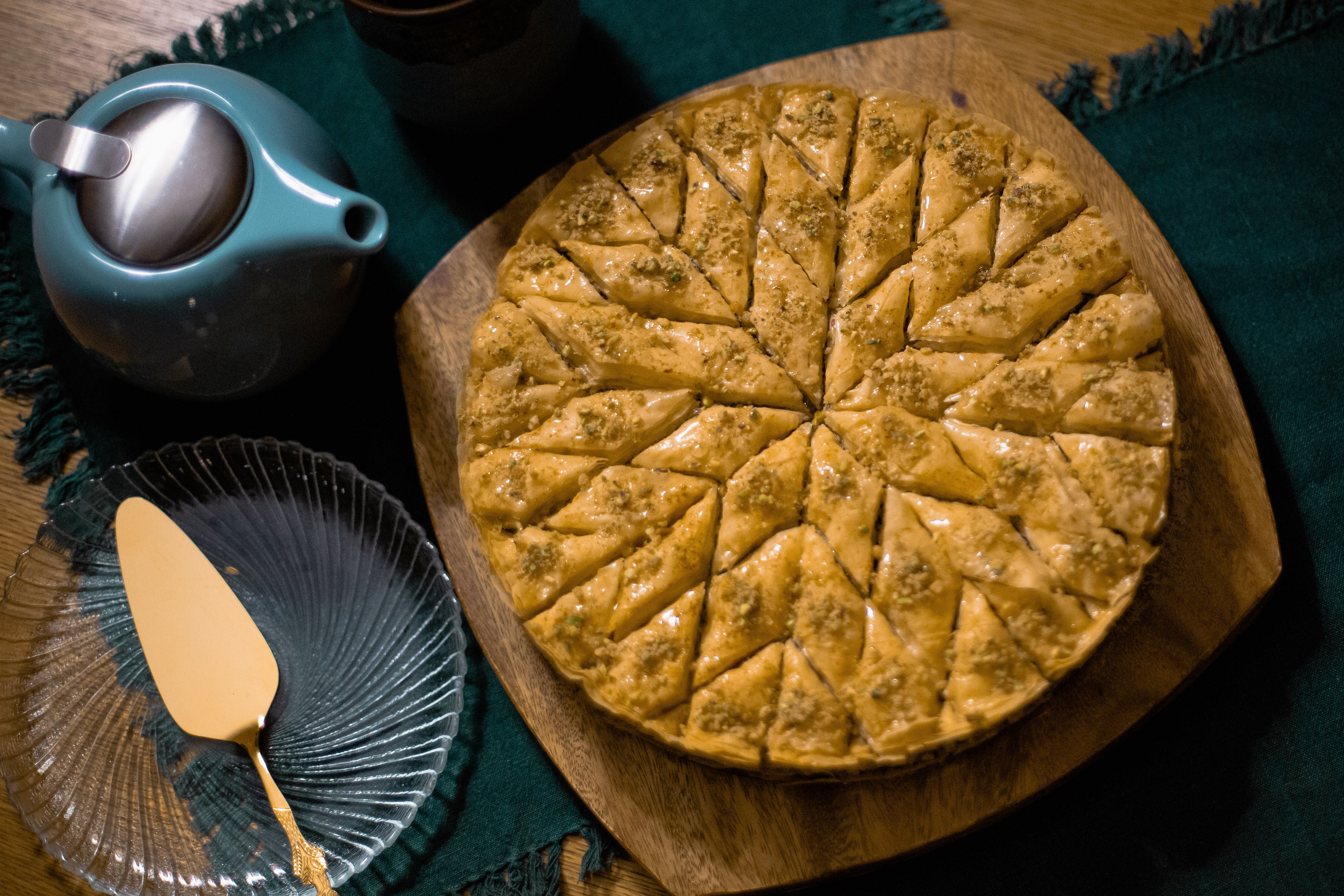 round baklava cut into a star pattern next to a teapot and serving knife