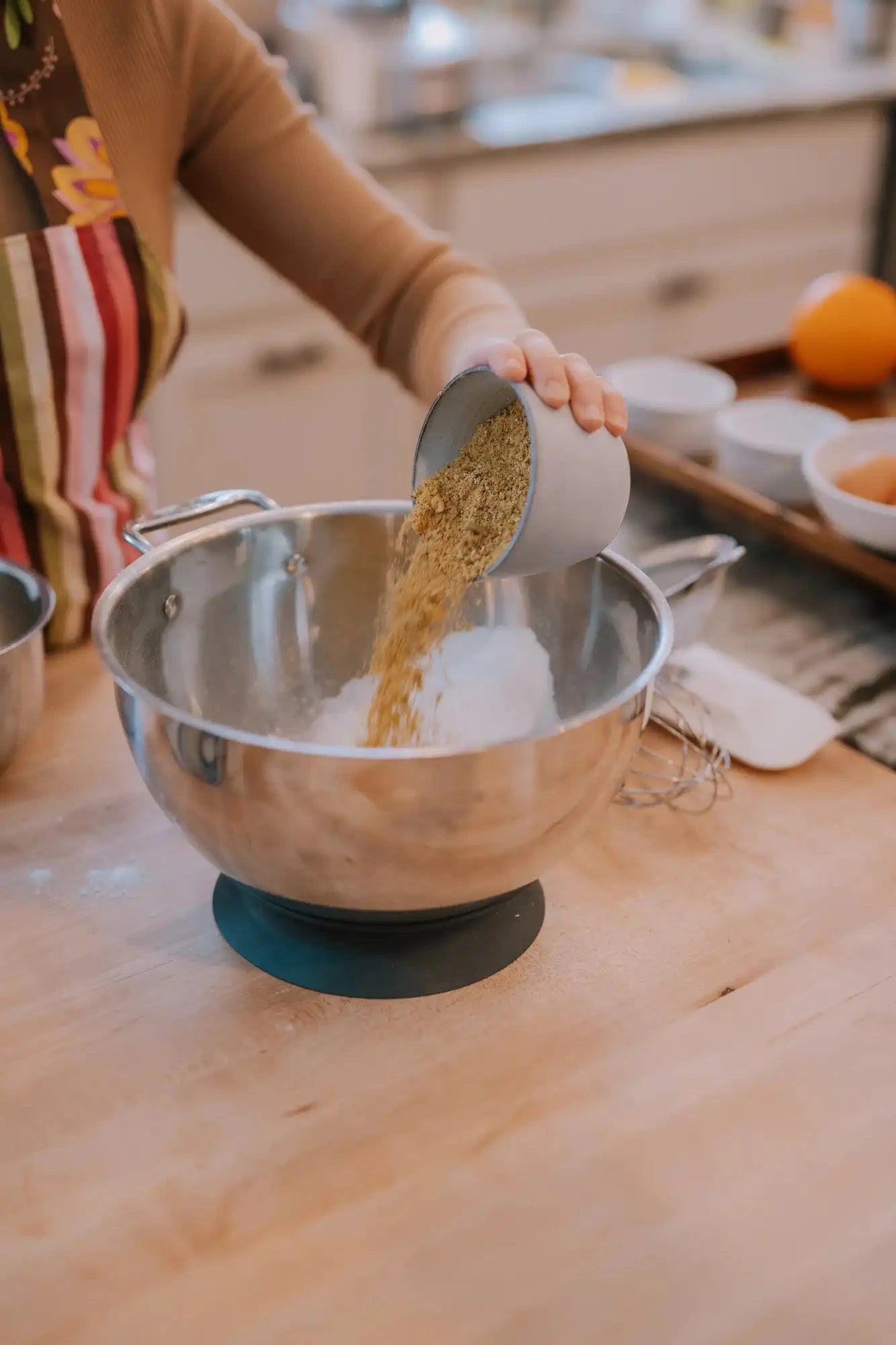hand adding pulverized nuts and spices to dry ingredients