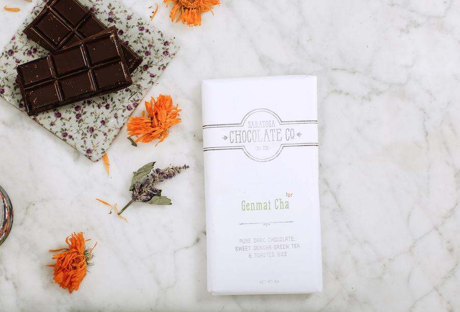 dark chocolate displayed on a cloth napkin next to wrapped Saratoga Chocolate Co Genmai Cha dark chocolate bar