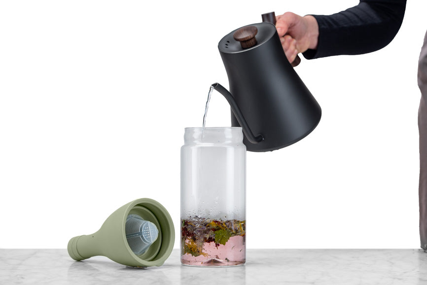 water being poured into an iced tea bottle over an herbal tisane